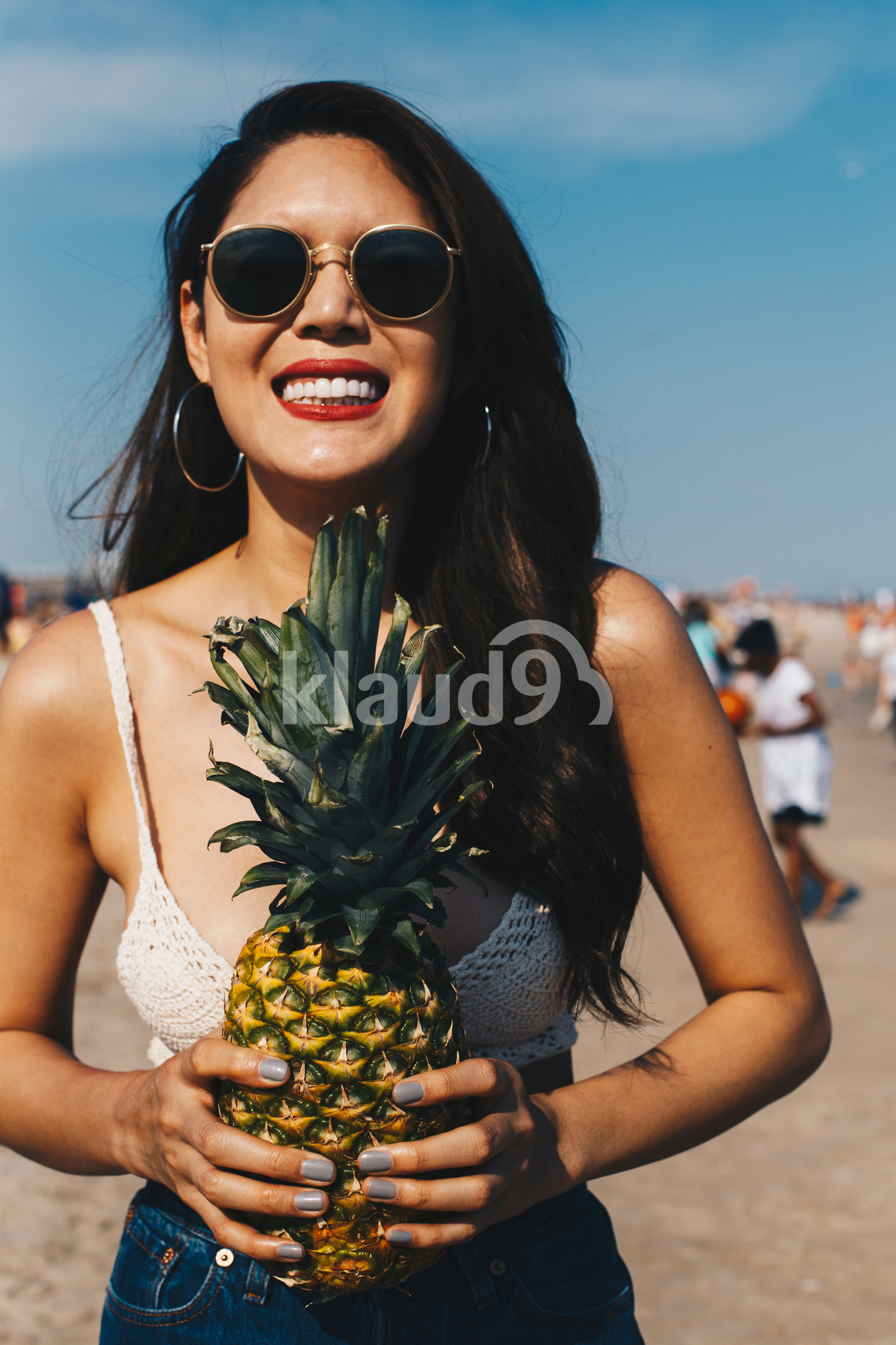 A beautiful girl holding the pineapple and having fun on the beach