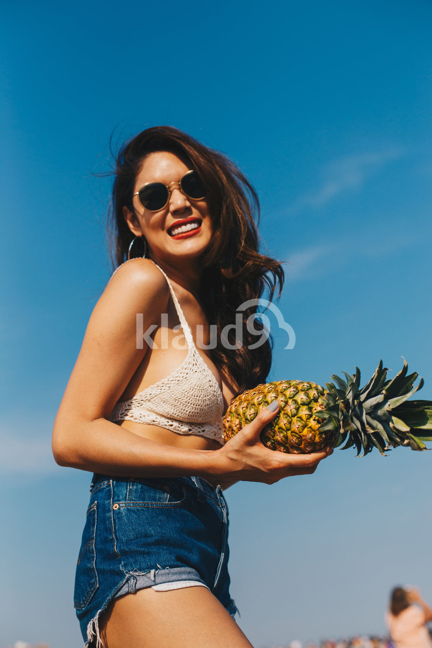 A beautiful girl holding the pineapple and having fun on the beach