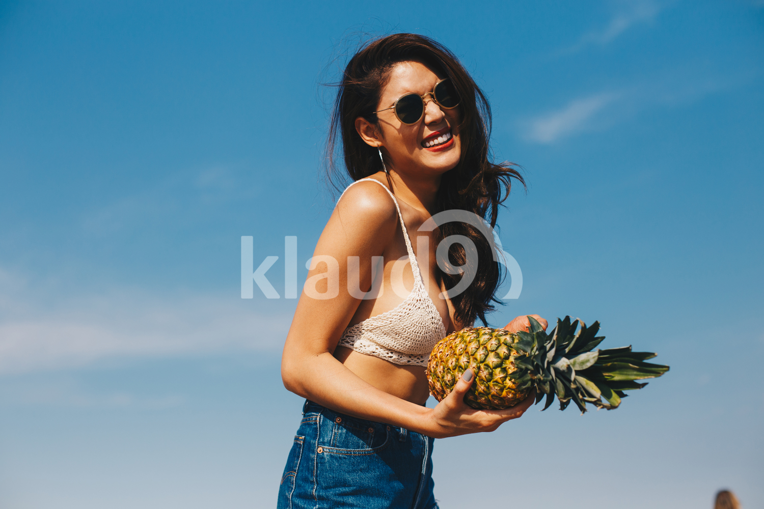 A beautiful girl holding the pineapple and having fun on the beach