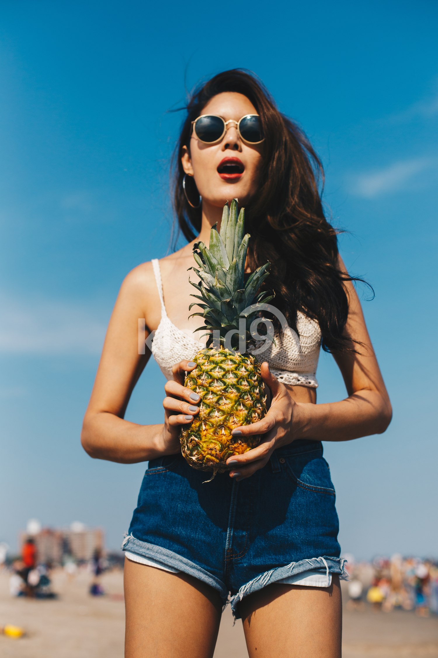 A beautiful girl holding the pineapple and having fun on the beach