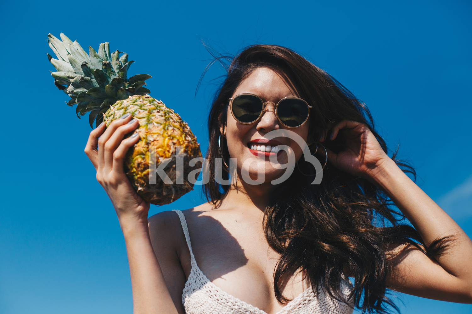 A beautiful girl holding the pineapple and having fun on the beach