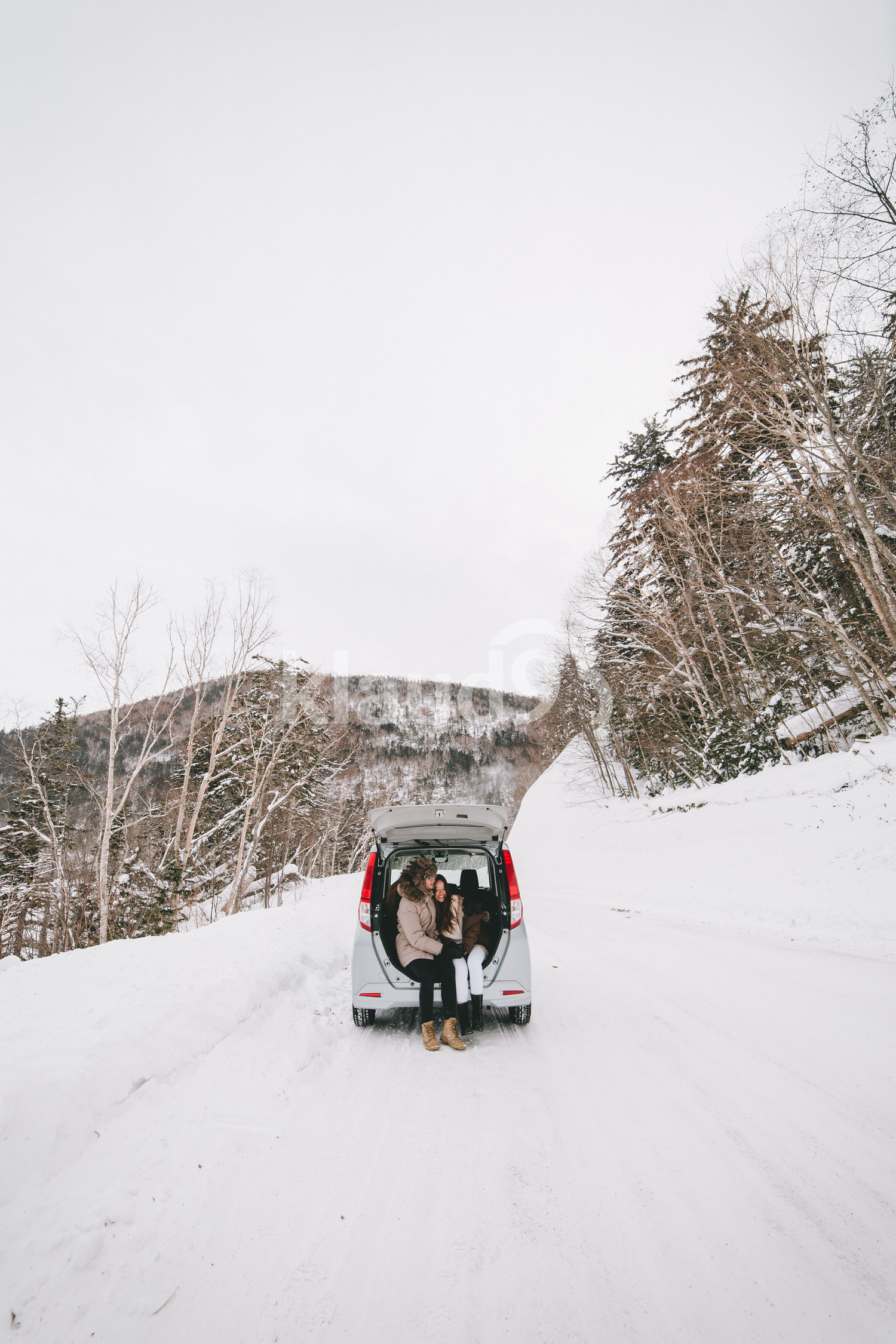 Asian couple sitting behind car boot