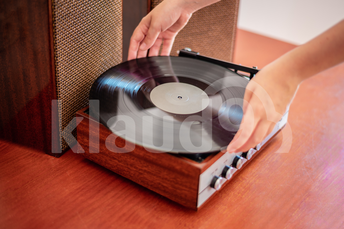 Hands put a vinyl on an old wooden turntable