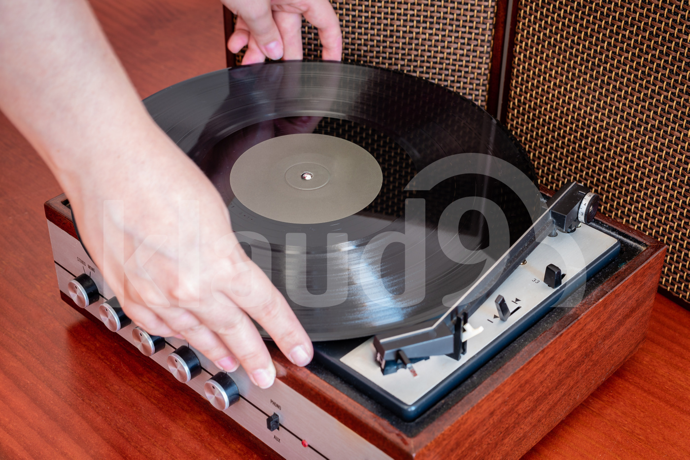 Hands put a vinyl on an old wooden turntable