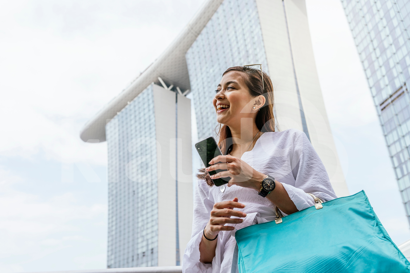 Woman standing holding mobile and handbag