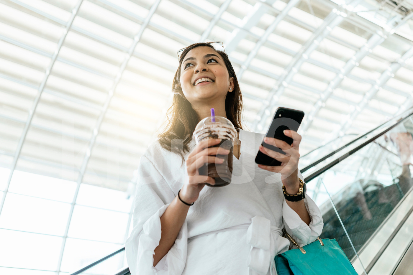 Woman using mobile while drinking a coffee