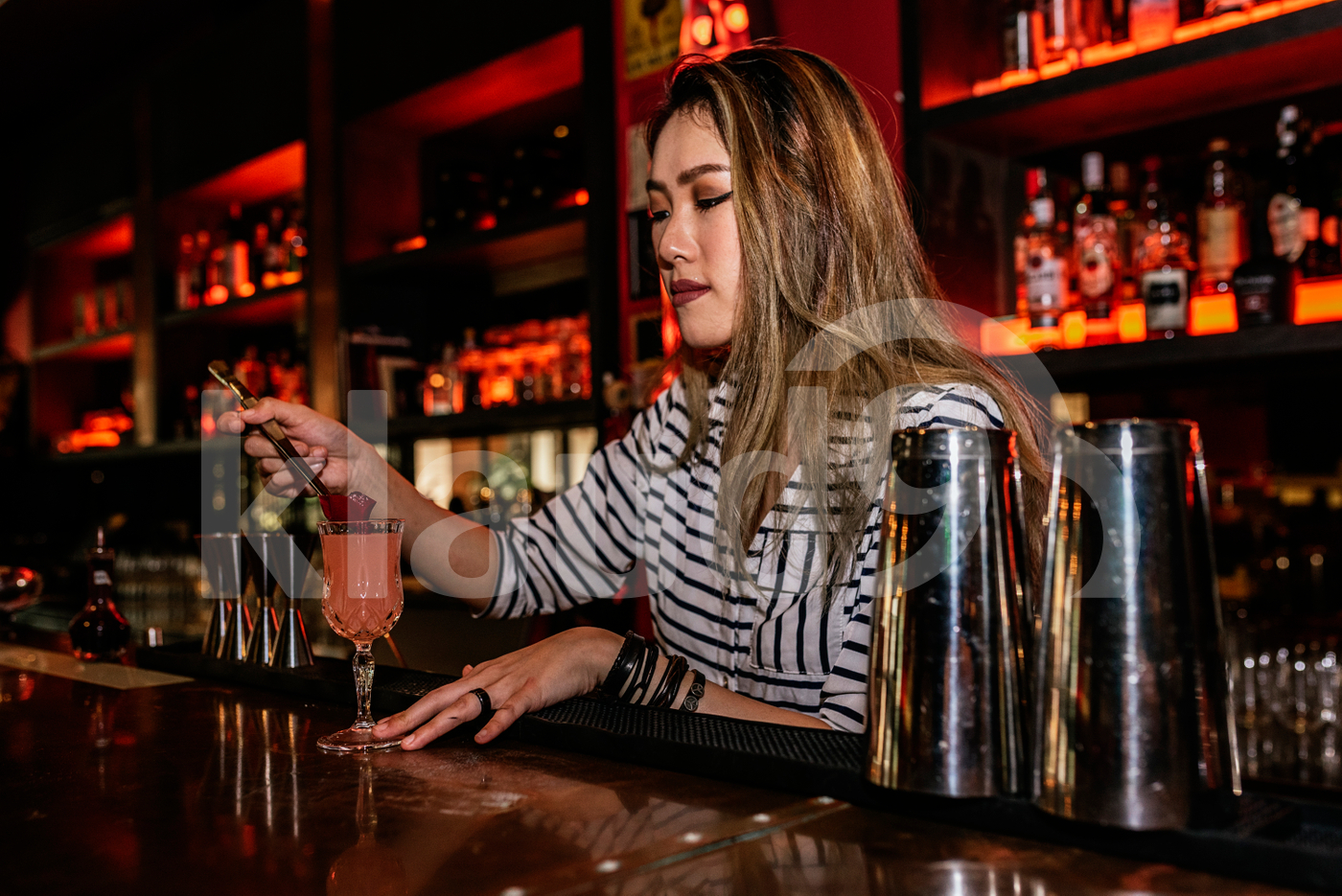 Female Asian bartender preparing a drink