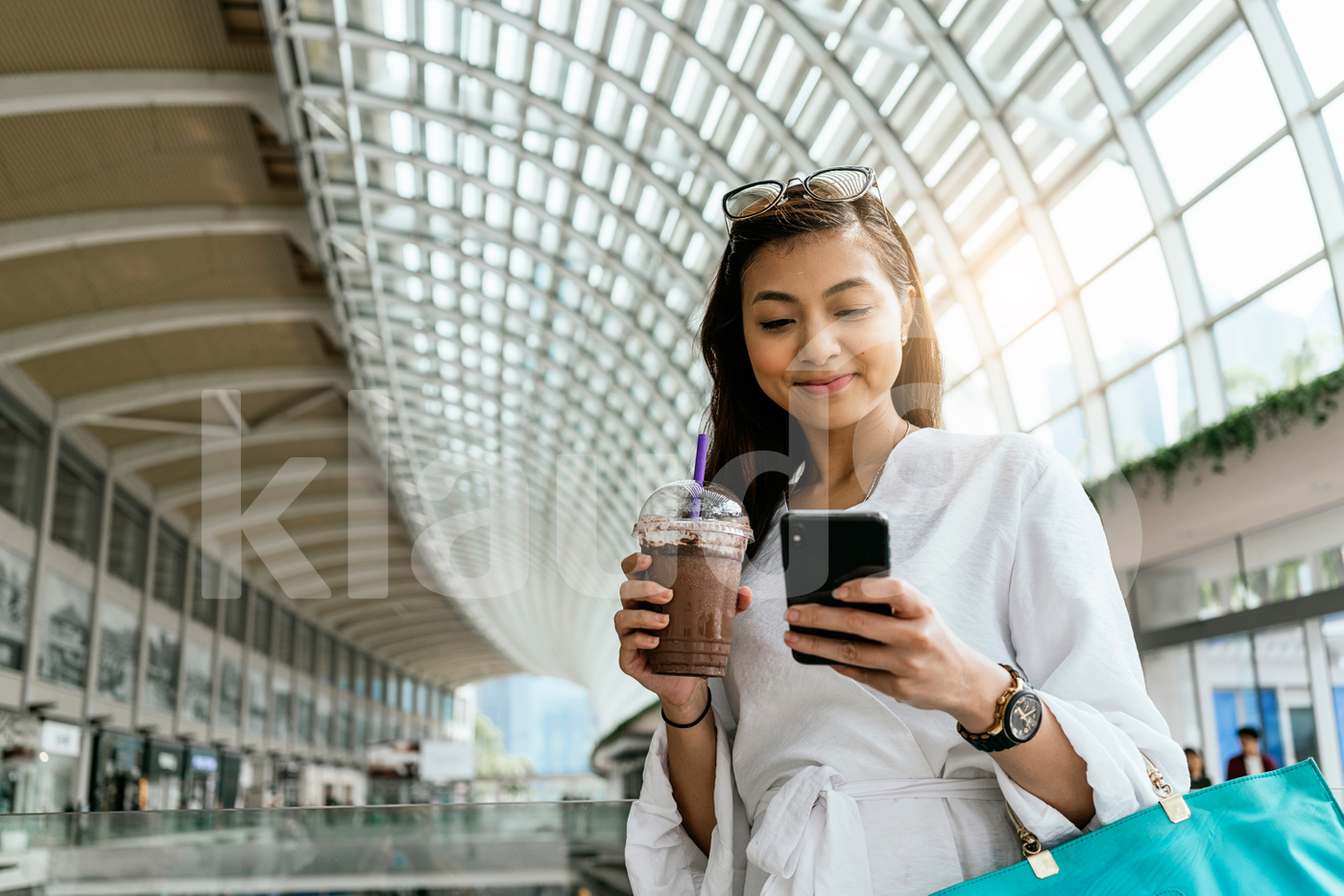 Woman using smartphone while drinking