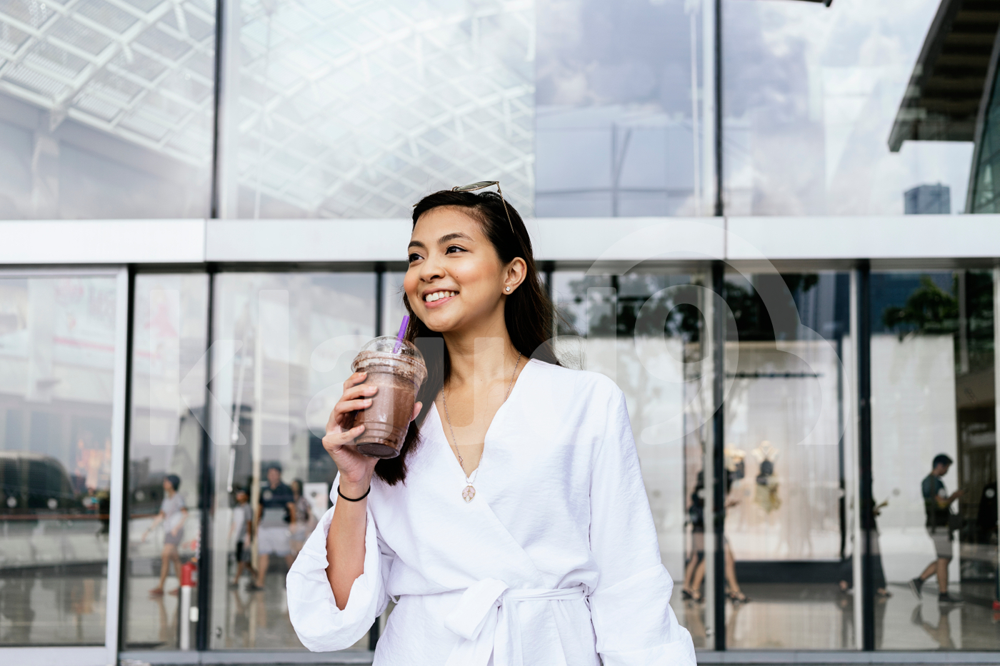 Young adult Asian woman standing in the mall holding a cup
