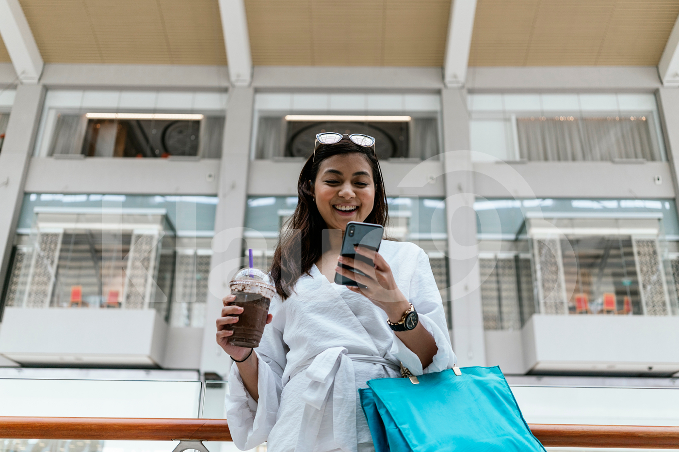 Woman using smartphone while holding a coffee