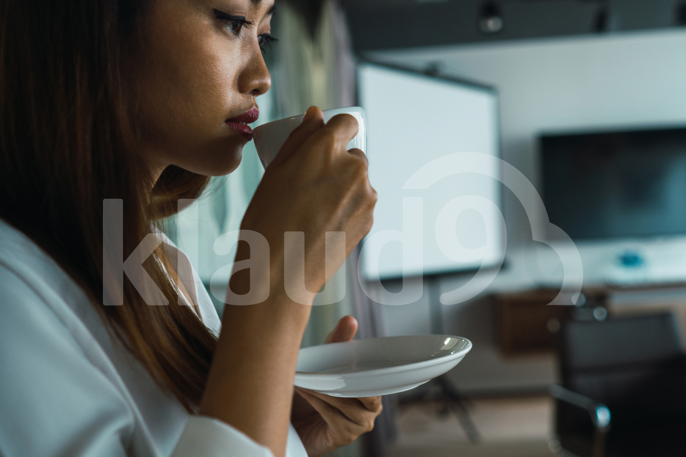 Asian woman standing in the office drinking coffee