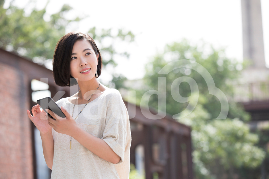 Beautiful young Chinese woman holding a smart phone