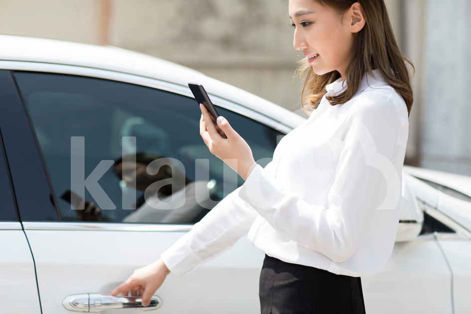 Young Chinese businesswoman opening car door