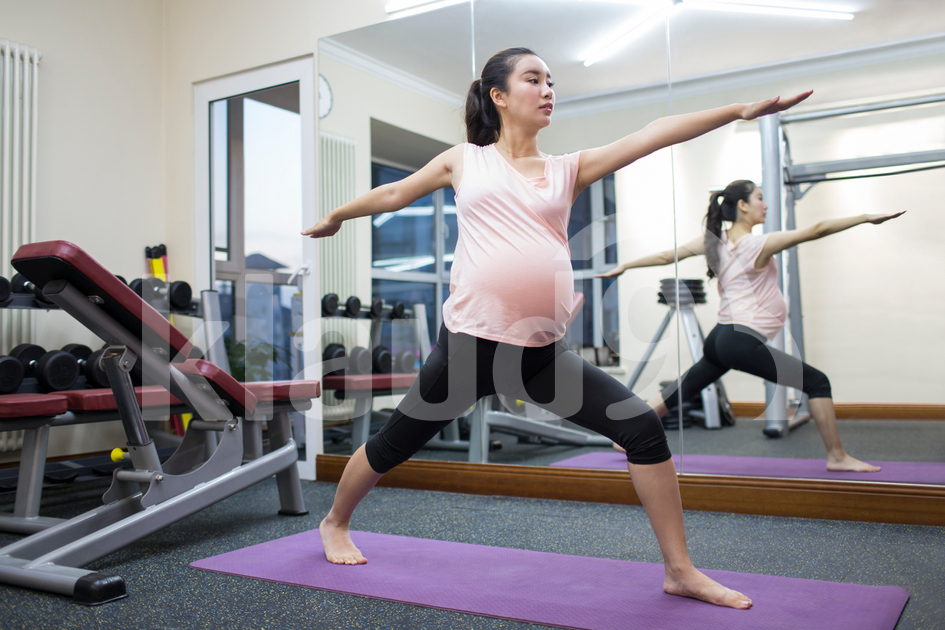 Pregnant Chinese woman exercising at gym