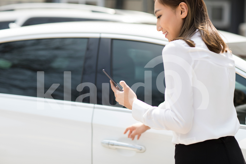 Young Chinese businesswoman opening car door