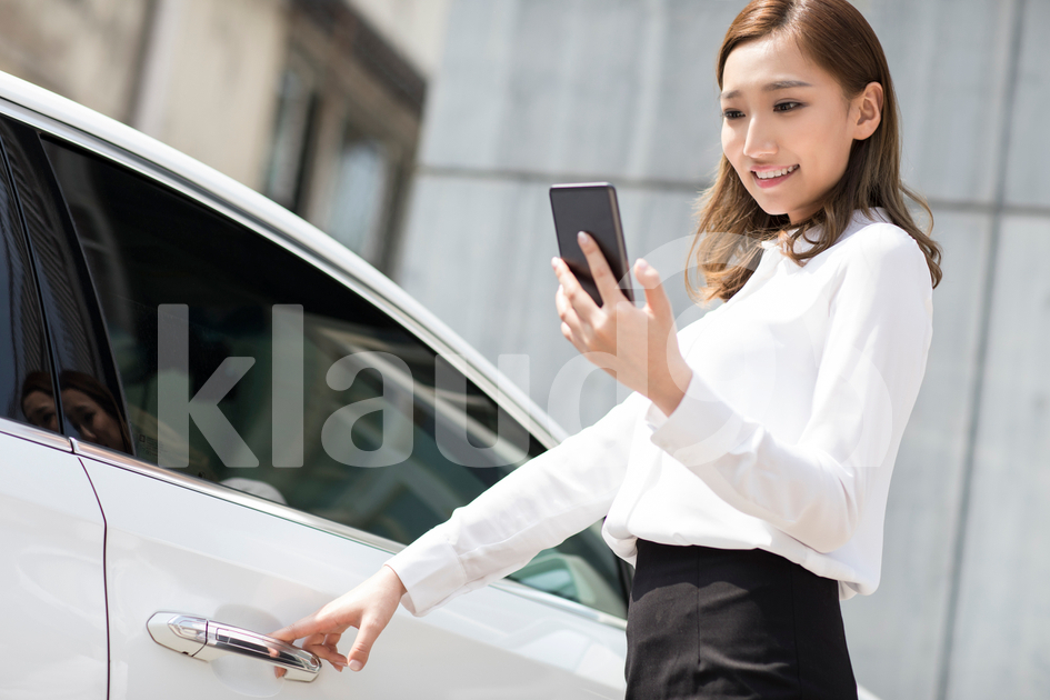 Young Chinese businesswoman opening car door