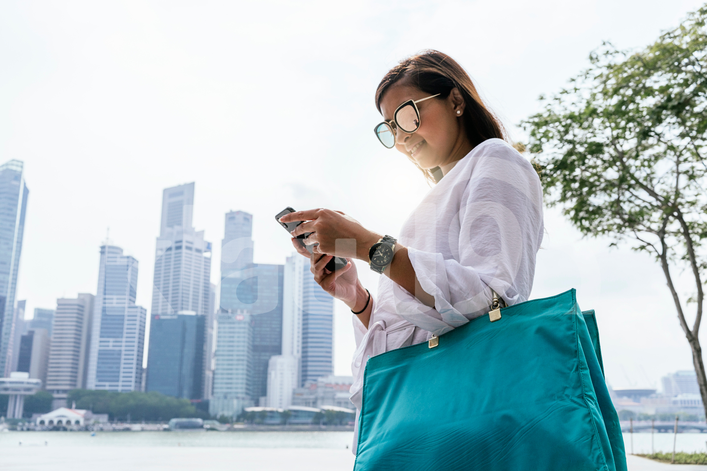 Young Asian woman  using phone, with city as a backdrop