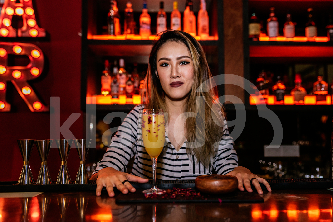 Portrait of female Asian bartender posing with a drink