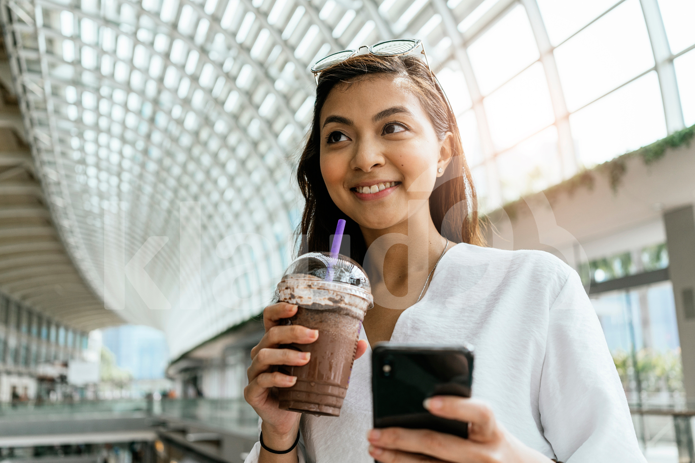 Asian woman using smartphone while drinking a coffee