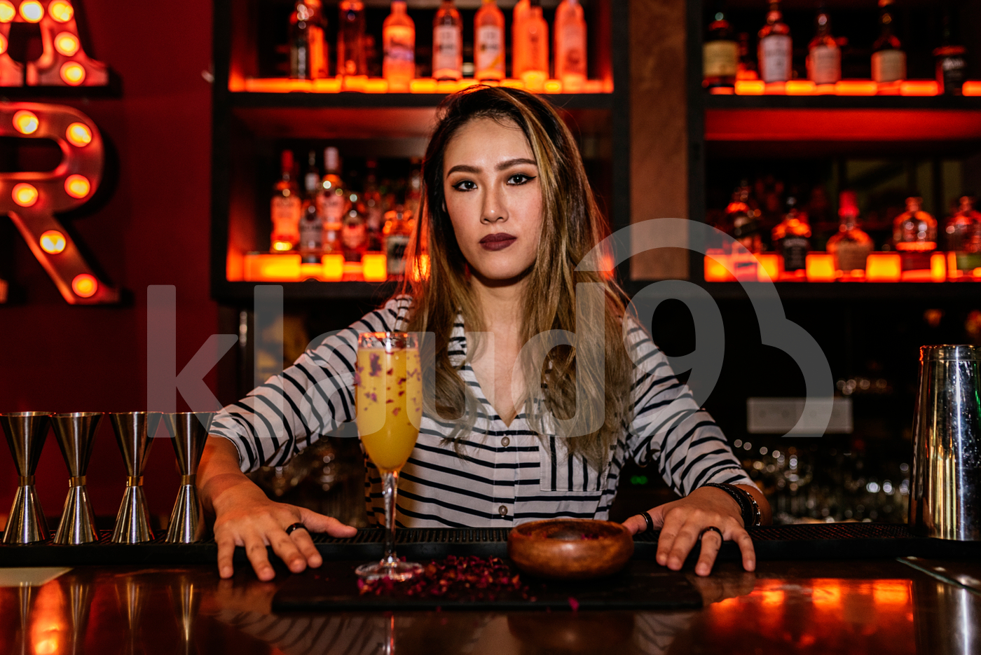 Portrait of female Asian bartender posing with a drink